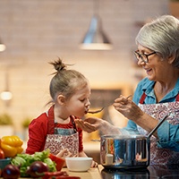 Little girl with older woman taste-testing homemade vegetable soup