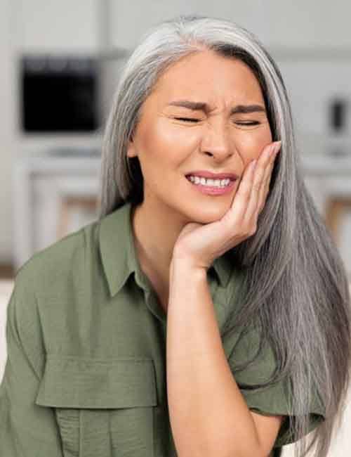 a woman holding her cheek due to tooth pain