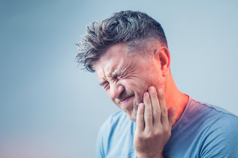 person with root canal holding cheeck